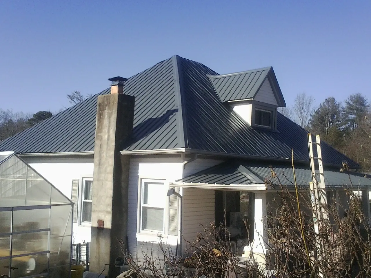 Dark blue standing seam metal roof on a white farmhouse with dormer — Slate & Tile Roof Repair by Roofing Brothers in Owings