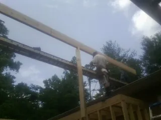 Carpenter setting a ridge beam over a new addition frame — Ice Dam Removal by Roofing Brothers in Owings