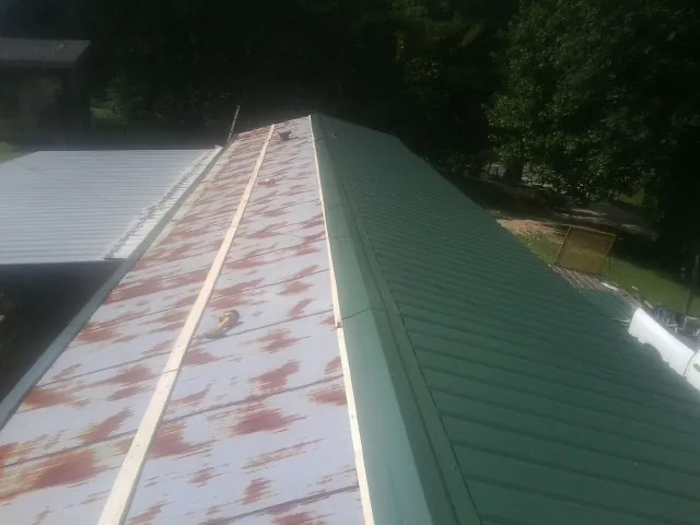 Old rusted panels beside newly installed green metal roofing — Wind Damage Roof Repair by Roofing Brothers in Owings