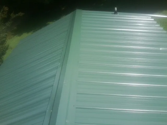 New green metal panels meeting at the ridge of a roof — Flat Roof Repair work by our crew in Owings