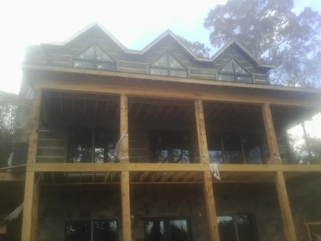 Dormers and porch framing on a large log home under construction — Roof Coating work by our crew in Owings