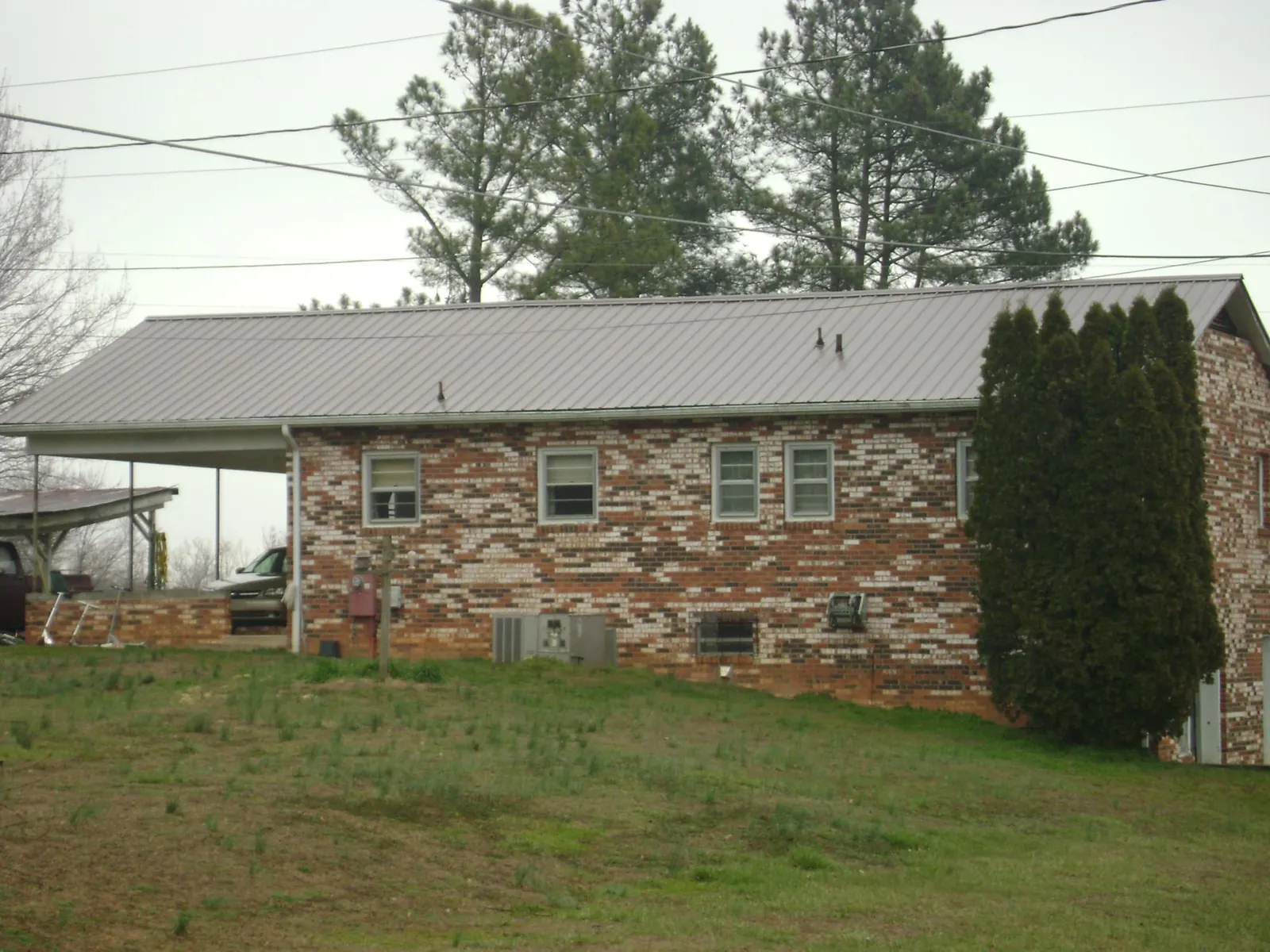 Gray metal roof on a brick split level home with a carport in Owings