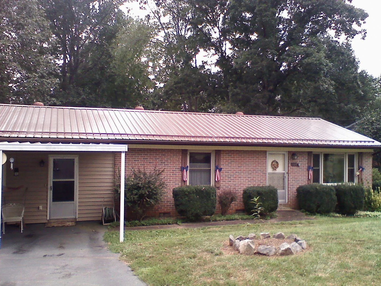 Bronze metal roof and carport on a brick ranch home — Roof Repair work by our crew in Owings