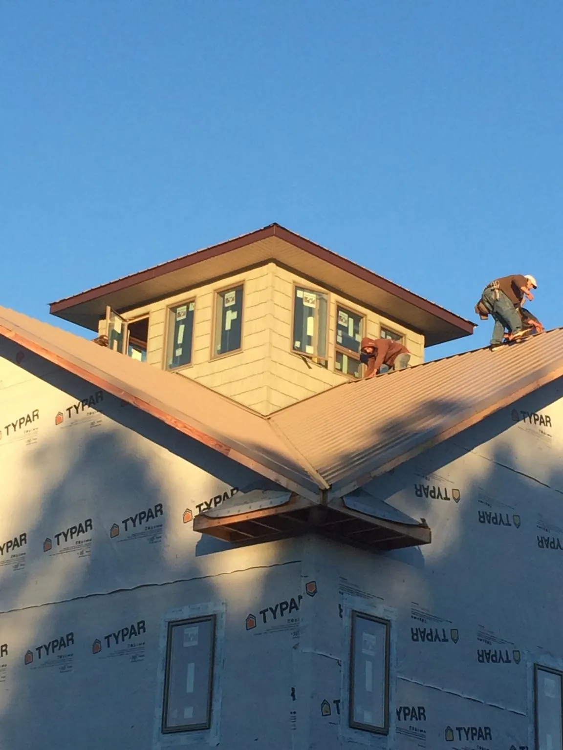 Roofers working around a rooftop cupola on a new metal roof at sunset — Roof Waterproofing in Owings by Roofing Brothers